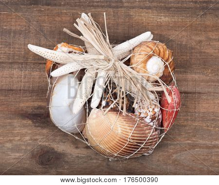Decorative bag of various seashells from Red Sea on vintage wooden tray