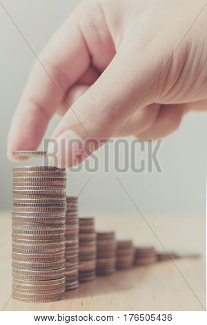 Hand of male or female putting coins on money stack first step growing growth saving money. Concept finance business investment