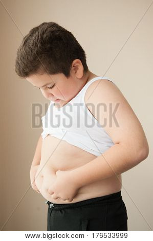 fat boy in a t-shirt holding his stomach