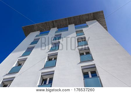 Modern residential building with white facade and balconies. Bottom view.