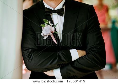 Pink peon boutonniere pinned to a grooms blue jacket
