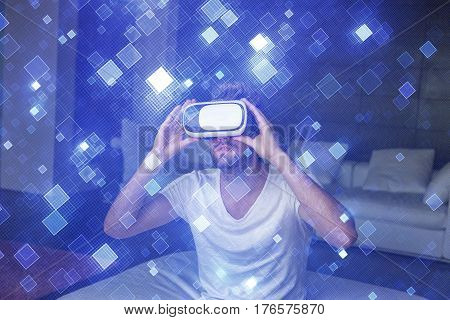 Young man with headset playing virtual reality with blue glowing suare tiles