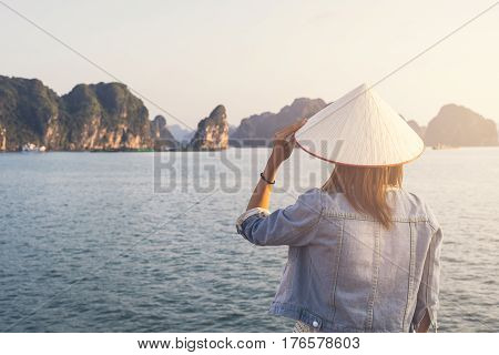 Woman traveler with Non La (Vietnam hat) looking beautiful natural view at Halong bay in Vietnam
