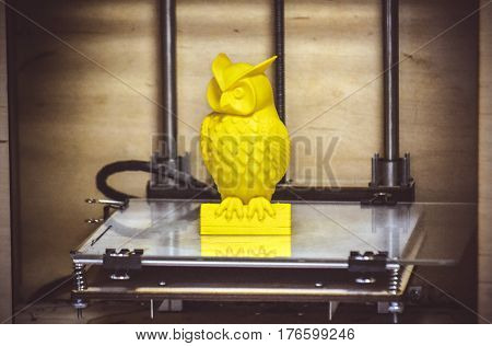 Modern 3D printer printing figure close-up. Automatic three dimensional 3d printer performs plastic yellow colors modeling in laboratory. Progressive modern additive technology