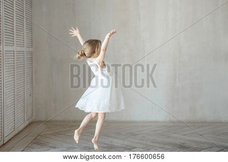 Little girl is playing in a room in a beautiful dress