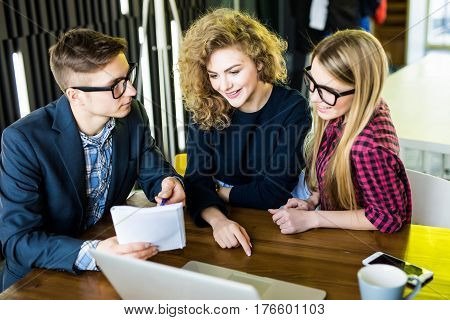 Group Of Friends Working On Their Small Business Modern Office. Man Show On His Notice On Notebook