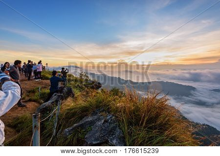 CHIANG RAI THAILAND-OCT. 25 2016: Group of tourist taking photos and waiting for the sunrise over the cloud scape on peak mountains in winter at Phu Chi Fa Forest Park OCT. 25 2016 in Thailand