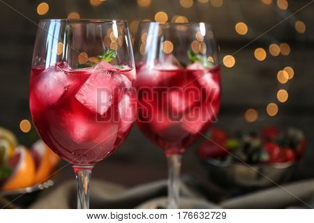 Glasses of delicious wine spritzer on blurred lights background