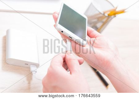 Hand connecting smart phone to the power bank with microUSB cable