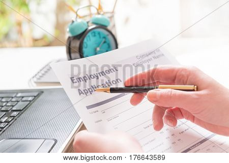 Blank employment application form in hands on a desk