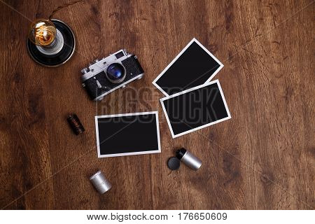 Vintage photo camera. Blank photo frames. Retro lamp light bulb. Old camera rolls. Wooden rustic background.