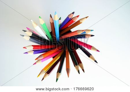 A lot of colored pencils inside a tin can on the white background.