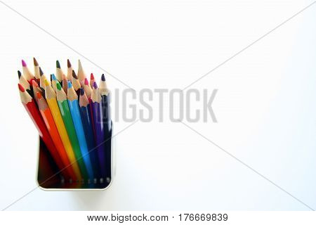 A lot of colored pencils inside a tin can on the white background.