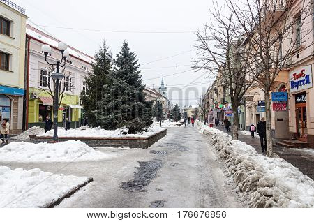 Mukachevo Ukraine - January 31 2017: Dukhnovicha street in center of Mukachevo. Dirty snow on a roadside nasty winter day.