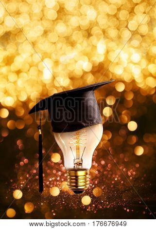 congratulations graduates cap on a lamp bulb with glitter lights grunge background.