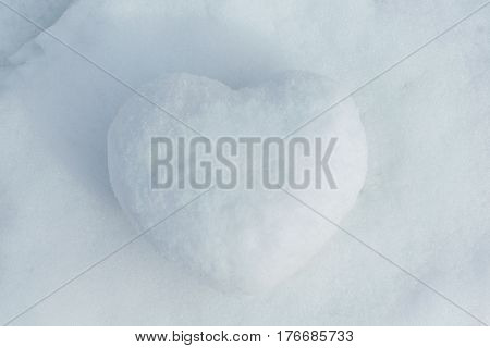 In winter the white snow lies cobbled together a snowball in the shape of a heart. On the street the day and the sun is shining. Cold and frosty. Can be used as a gift a surprise.