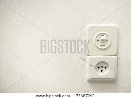 Old vintage switch and socket on a white plastered wall