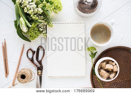 Feminine flatlay with flowers and ccoffee, empty notepad with copy space