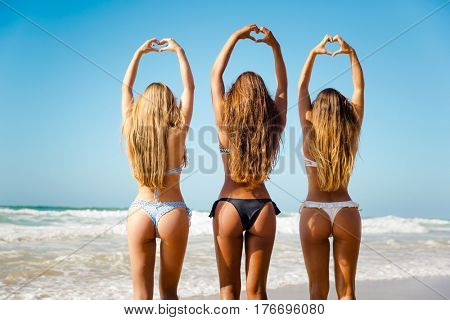 Beautiful girls in the beach making hearts with their hands
