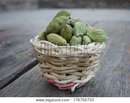 Cardamom in bamboo basket on wooden board