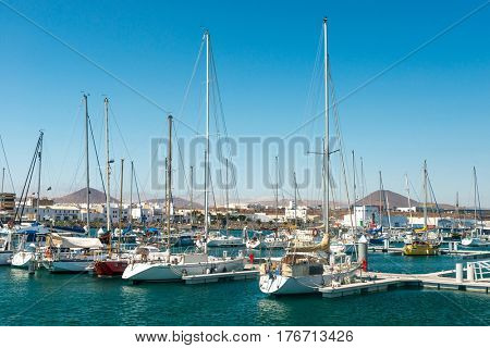 Expesive yachts with their masts up, near lovely city harbor, Spain