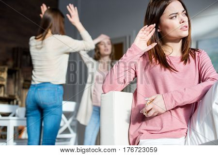 Three irritated young women quarreling and gesturing at home