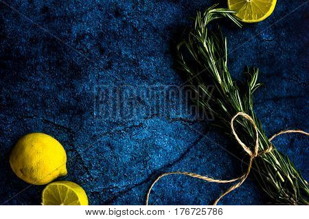 Rosemary and lemon on a dark concrete background. Space for text