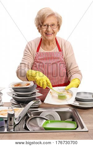 Mature woman cleaning the dishes with a brush and looking at the camera isolated on white background