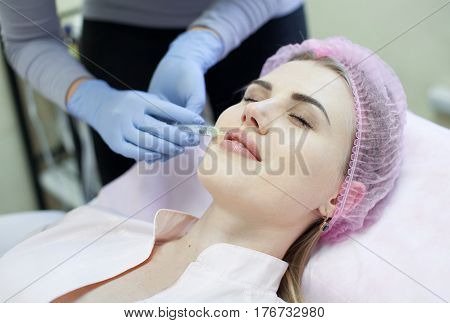Woman gets injection in her face. Beauty woman giving injections. Young woman gets beauty facial injections in the cosmetology salon. Face aging injection. Aesthetic Medicine, Cosmetology