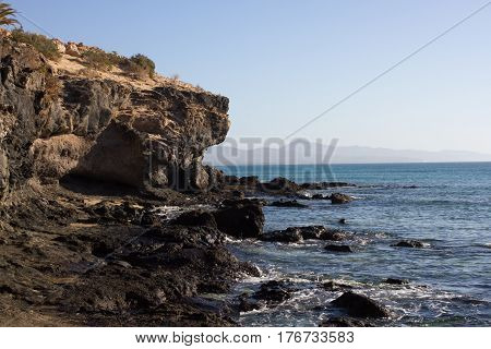 Black rocks of Costa Calma beach. Blue sea line. Playa Barca, Fuerteventura, Canary islands, Spain. Istmo de la pared view