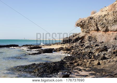 Black rocks of Costa Calma beach. Blue sea line. Playa Barca, Fuerteventura, Canary islands, Spain. Istmo de la pared view