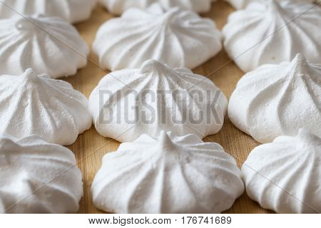 Fresh mini meringues on a wooden background. Close up