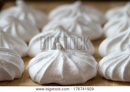 Fresh mini meringues on a wooden background. Close up