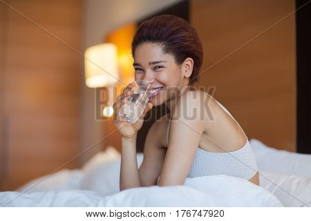Young Beautiful Woman With Glass Of Water In A Bed.