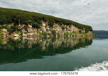 Beautiful coast of the Kurile Lake is reflected in the water.