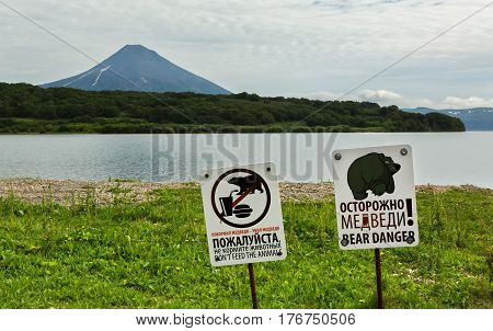 Kamchatka Peninsula, Russia - August 13, 2016: Signs warn of the danger of meeting tourists with bears in the background of Kurile Lake and Ilyinsky volcano. South Kamchatka Nature Park.