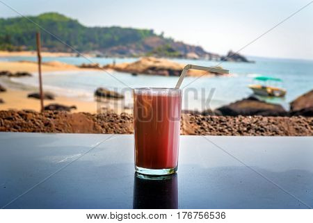 Strawberry cocktail with a straw in a glass stands on the table on background of sea. breakfast