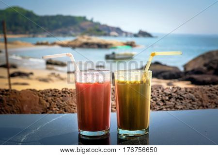 Two glasses with cocktails in glasses on the background of sea and sky. Coffee cocktail and a strawberry smoothie for Breakfast.