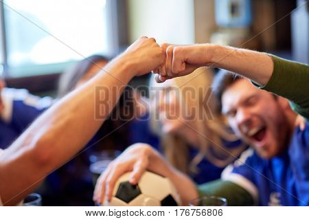 people, soccer, leisure and sport concept - happy friends or football fans with ball celebrating victory at bar or pub