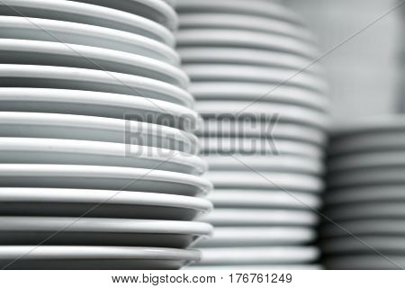 A lot of white plates on a white background, stacked evenly on each other