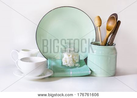 Crockery tableware utensils and other different white and turquoise stuff on white table-top. Kitchen still life as background for design. Image with copy space.