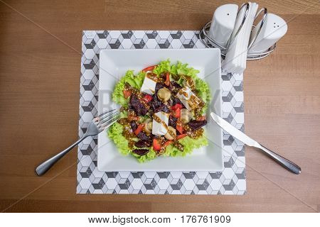 Fresh vegetable salad with cheese on a white plate with cutlery Salt and pepper. Greek vegetable salad with feta cheese