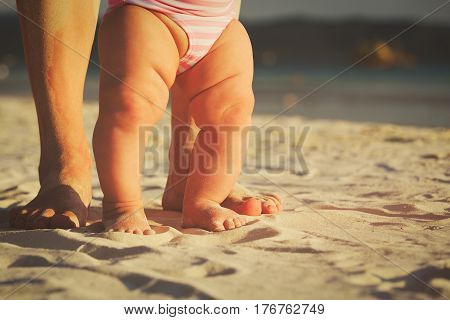 mother and little baby feet making first steps on beach