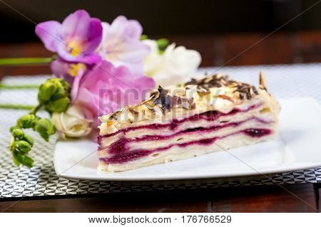 Piece of delicious cake Blueberry Vanilla Cake Piece of cake on a white plate with flowers close-up on a wooden table.