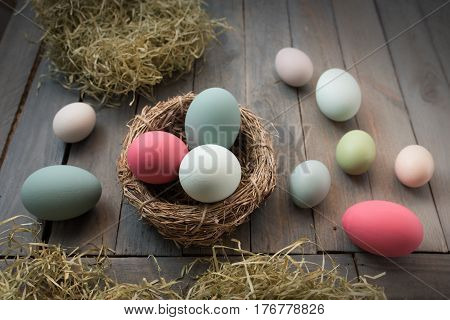 Decoration with colorful easter eggs in in a nest on a old shabby wooden table