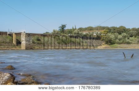 Overlooking at Dam of Cornalvo Reservoir from stony shore. This dam was declared National Monument on Dec 13th 1912 and it is still in use nowadays. Extremadura Spain