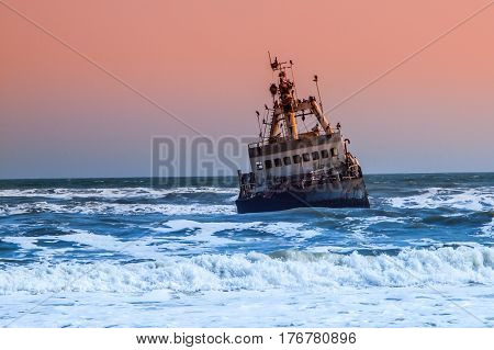 Shipwreck in wild Atlantic Ocean at Skeleton Coast, Namibia, Africa.
