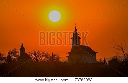 Two churches on a hill in the warm light of the sunset