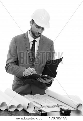Noting carefully. Monochrome shot of a professional constructionist writing on his clipboard profession notes info developer businessman builder foreman architect urban profession occupation concept