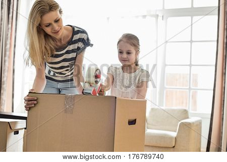 Mother and daughter packing cardboard box at home